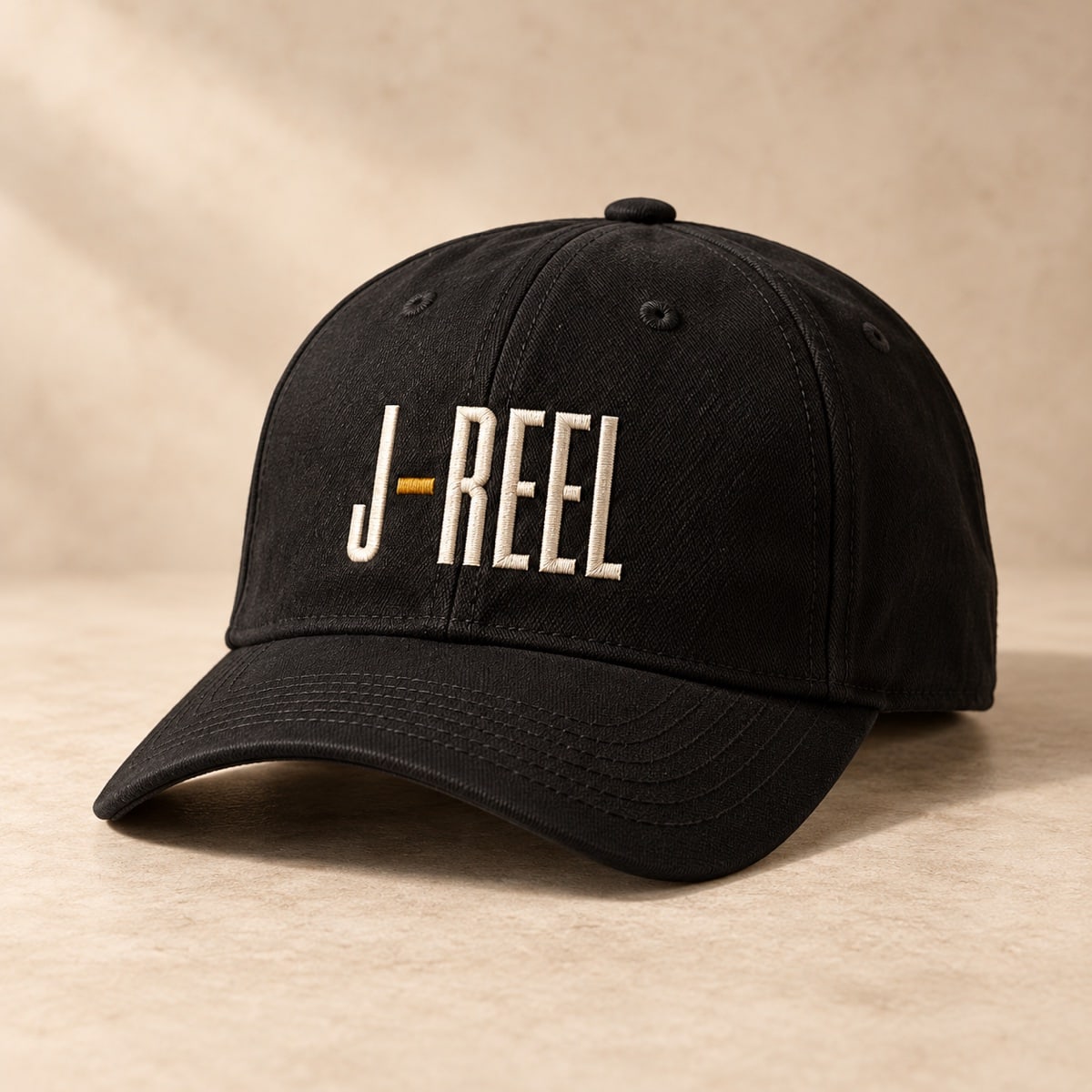 Original concept black curved-brim baseball cap with an ivory and gold J-Reel mark