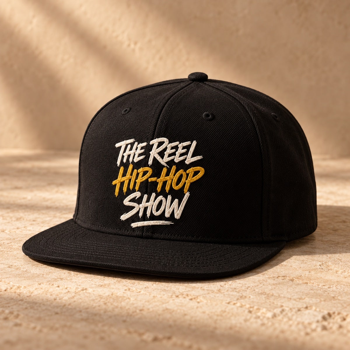 Original concept black flat-brim fitted cap with The Reel Hip Hop Show lettering in ivory and gold